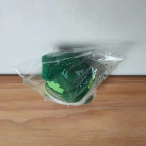 Detail of St. Patrick's Day green plush gnome hat with shamrock in plastic packaging