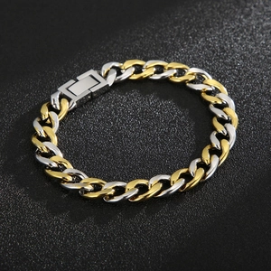 Macro detail of two-tone gold and silver Cuban link bracelet on black texture background