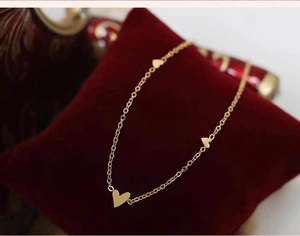 Primer plano de un collar dorado con corazones sobre un cojín de terciopelo rojo