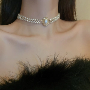 Détail d'un collier doré double épaisseur avec perle baroque sur le cou d'un mannequin