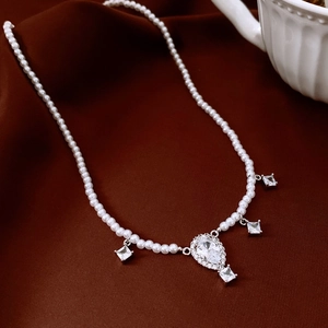Close-up of pearl necklace with water-drop zircon pendant on luxury silk background