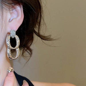 Close-up of model wearing silver earrings with interlocking rings and pavé zircon details