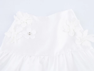Close-up of white sweet style top featuring 3D floral appliques and central rhinestone detail
