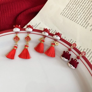 Close-up of red tassel earrings with golden Fu character charms and dragon motifs
