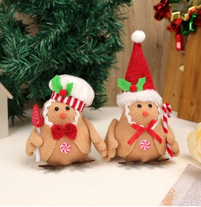 Pair of plush gingerbread bird ornaments with red hats on a warm Christmas tree branch