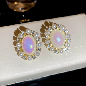 Macro shot of French vintage earrings featuring oval opals, pearls, and zircons on gold metal