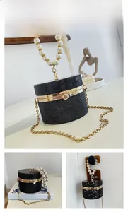 Detail of black rhinestone cylinder evening bag with pearl handle and golden chain