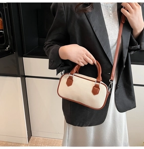 Detail of a color-block Boston bag featuring off-white weave texture and brown leather trim