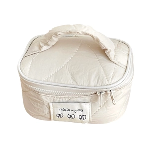 Quilted cream vanity case with bow embroidery and top handle for travel makeup storage