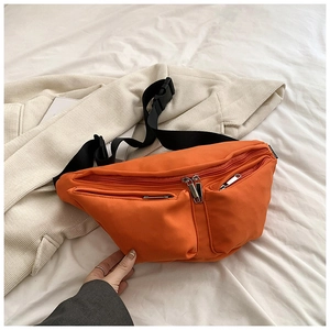 Macro view of bright orange waterproof nylon chest bag with zippers and wide shoulder strap