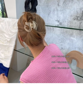Détail d'une pince à cheveux en acrylique beige tenant un chignon élégant sur un modèle