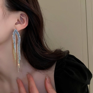 Gros plan de longues boucles d'oreilles à pompons en zircon bleu sur un modèle