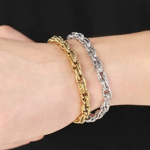 Macro detail of intertwined gold and silver rope chain bracelets on wrist with black background