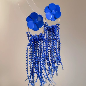 Macro shot of blue flower earrings with golden rings and cascading long bead tassels