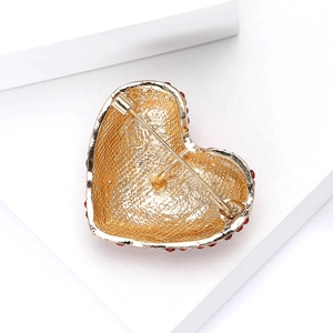 Gros plan du dos d'une broche coeur dorée montrant la texture et l'épingle de sûreté