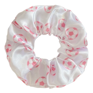 Détail d'un chouchou en satin blanc avec motif de football rose et texture lisse