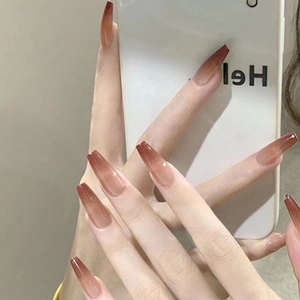 Detailed view of long coffin ombre press-on nails in amber and pink gradient finish