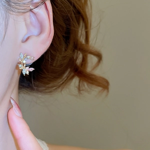 Close-up of sparkling floral branch stud earrings with pink and white crystals