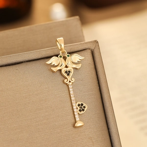 Macro shot of gold key pendant with green gemstone and angel wing design detail
