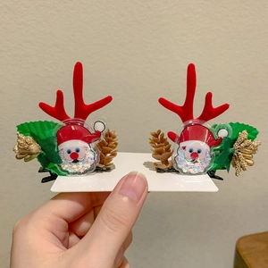 Detail of Christmas reindeer antler hair clips with Santa Claus and pine cone decor