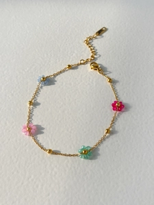 Close-up of golden necklace with colorful resin flower charms and lobster clasp detail