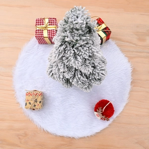 Plush white Christmas tree skirt on wooden floor with festive holiday decorations