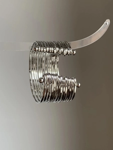 Detail of silver multi-layer metal wrap cuff bracelet with bead accents on clear stand
