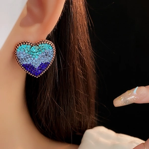 Close-up of vintage gold heart earrings with blue-green gradient rhinestones on model