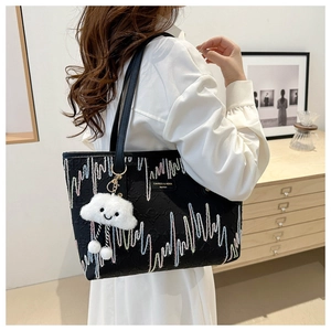 Detail of black embroidered tote bag with wavy patterns and cloud plush charm