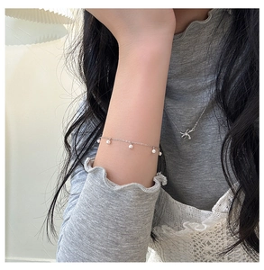 Primo piano di un bracciale in argento con perle bianche indossato da una modella