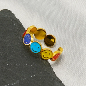 Détail d'une bague en acier doré avec des breloques smiley en émail coloré