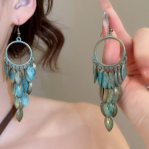 Close-up of vintage bronze and blue leaf tassel earrings worn by a model