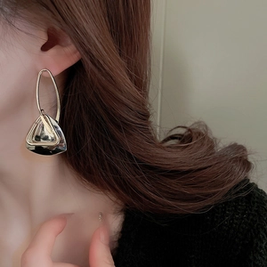 Detail of geometric metal earrings with gold and gunmetal triangular pendant on model