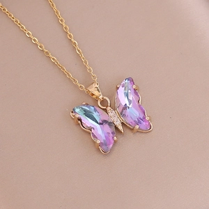 Close-up of golden butterfly pendant featuring pink gradient crystal and diamond accents
