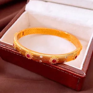 Bracelet vintage plaqué or 24K avec rubis et diamants sur un écrin de luxe rouge