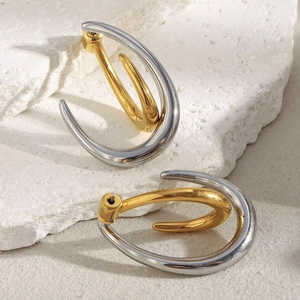 Detail of two-tone gold and silver curved C-shape earrings on textured white stones