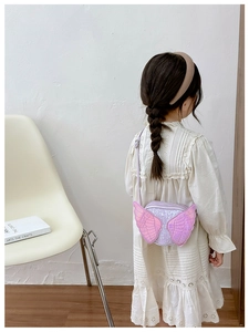 Girl wearing a glittery lavender angel wing crossbody bag over a white dress