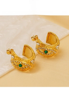 Gros plan de boucles d'oreilles œil porte-bonheur dorées avec malachite et cristaux