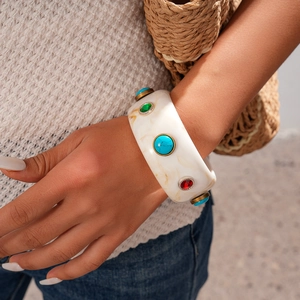 Close-up of resin cuff bracelet with blue and red gemstone inlays on model wrist