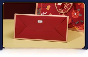 Detailed close-up of the reinforced bottom structure on a premium red gift paper bag
