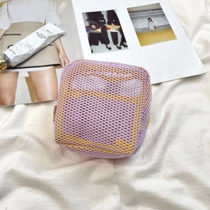 Close-up of a lavender mesh mini cosmetic bag with yellow zipper detail on fabric