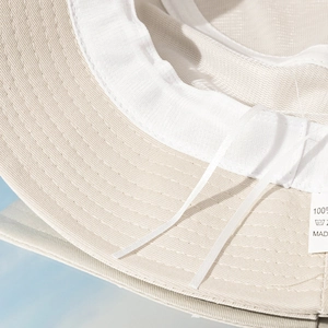 Detail view of beige cotton bucket hat interior with adjustable drawstring and stitching
