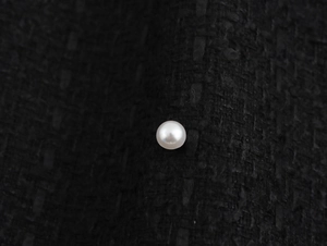 Vue détaillée du bouton perle élégant sur le tissu en tweed texturé de la robe licou