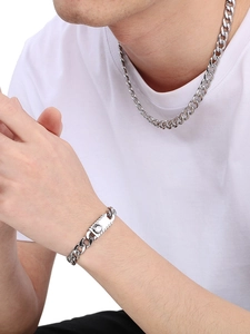 Close-up of hip hop silver stainless steel Figaro chain necklace and bracelet on male model