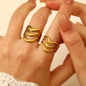 Detail showing two golden wavy stainless steel rings styled on a model's hand
