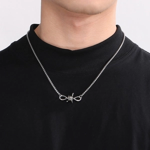 Detail of silver thorn knot necklace on black shirt background showcasing punk style