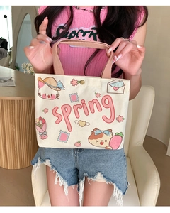 Close-up of a cream canvas tote bag with pink spring text and cute cat illustrations