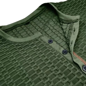 Gros plan sur la maille gaufrée vert militaire et les boutons noirs d'un Henley pour hommes