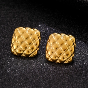 Macro shot of gold square quilted earrings with high-polish metallic finish