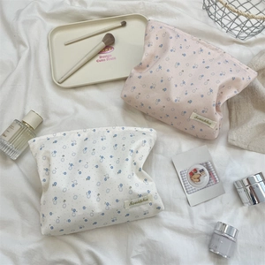 Detailed shot of floral cotton cosmetic bags with Sozakka label on soft white bedding